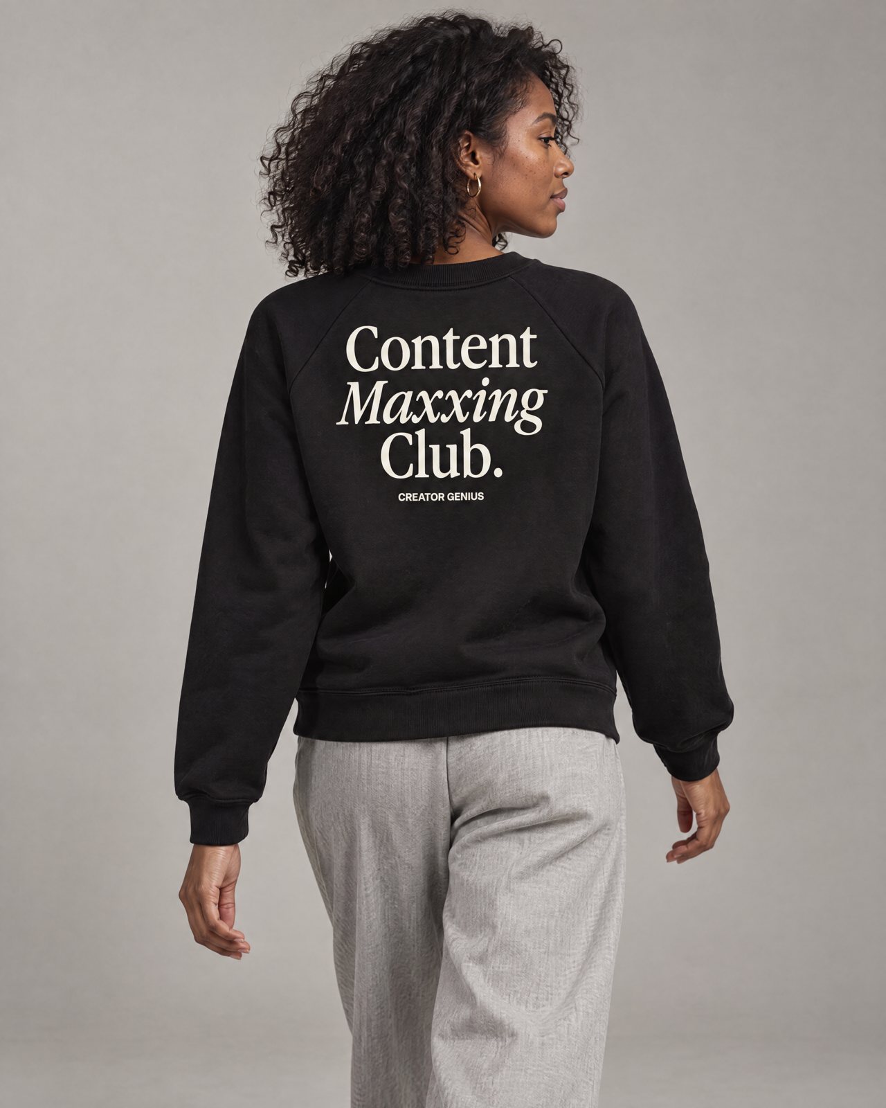 Model wearing the black Content Maxxing raglan fleece, back view, in a studio, lifestyle view